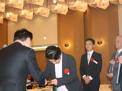 高橋理事長から表彰を受ける入賞社の代表
